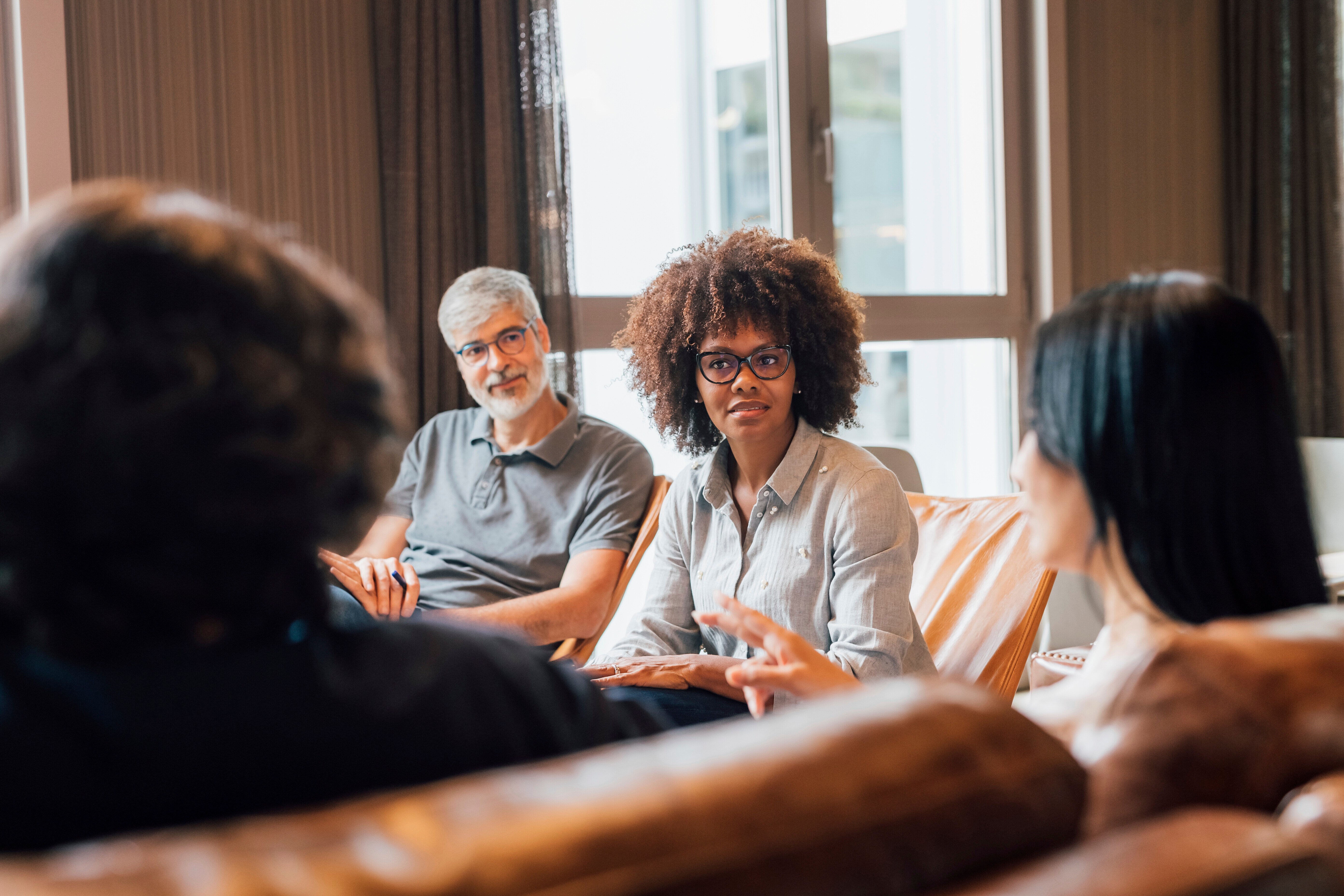 A group listens intently, as a member shares a thought during a group ketamine therapy session