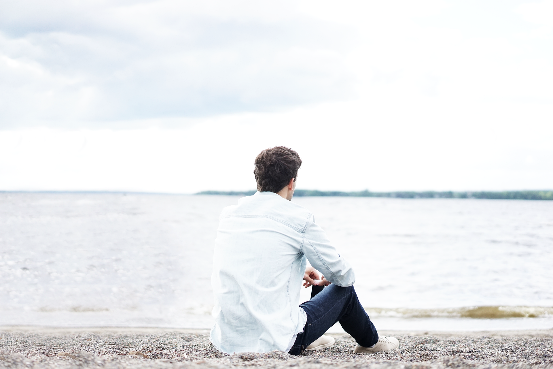 Young man sitting by the ocean enjoying the view