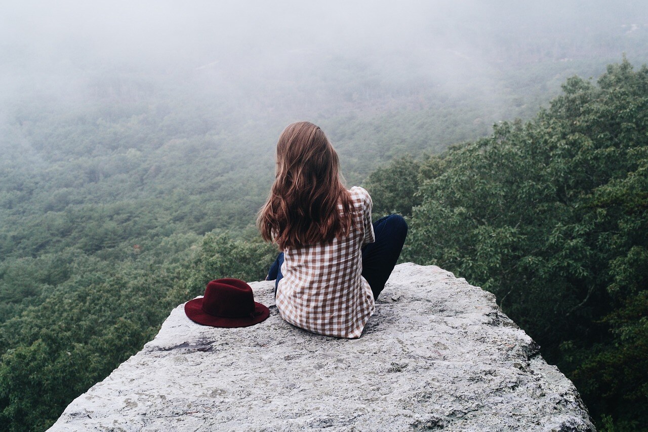 A young lady takes in a mountain-top view.